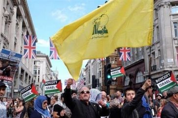 Manifestantes británicos con una bandera de Hezbolá