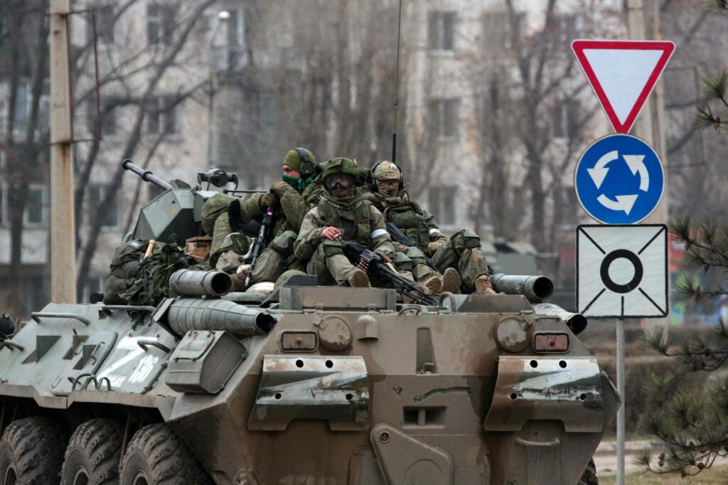 Servicemen ride atop a Russian armored vehicle in Armyansk, Crimea, on February 25, 2022. - Ukrainian forces fought off Russian invaders in the streets of the capital Kyiv on February 25, 2022, as President Volodymyr Zelensky accused Moscow of targeting civilians and called for more international sanctions. Pre-dawn blasts in Kyiv set off a second day of violence after Russian President Vladimir Putin defied Western warnings to unleash a full-scale invasion on on February 24, 2022, that quickly claimed dozens of lives and displaced at least 100,000 people. (Photo by STRINGER / AFP)