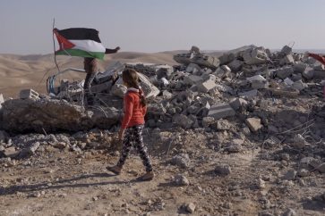 Una niña pasa junto a los restos de su escuela destruida