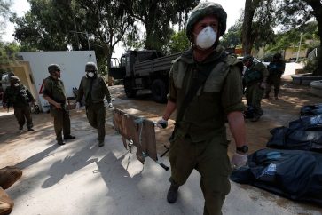 Soldados israelíes recogen a otros muertos en combates